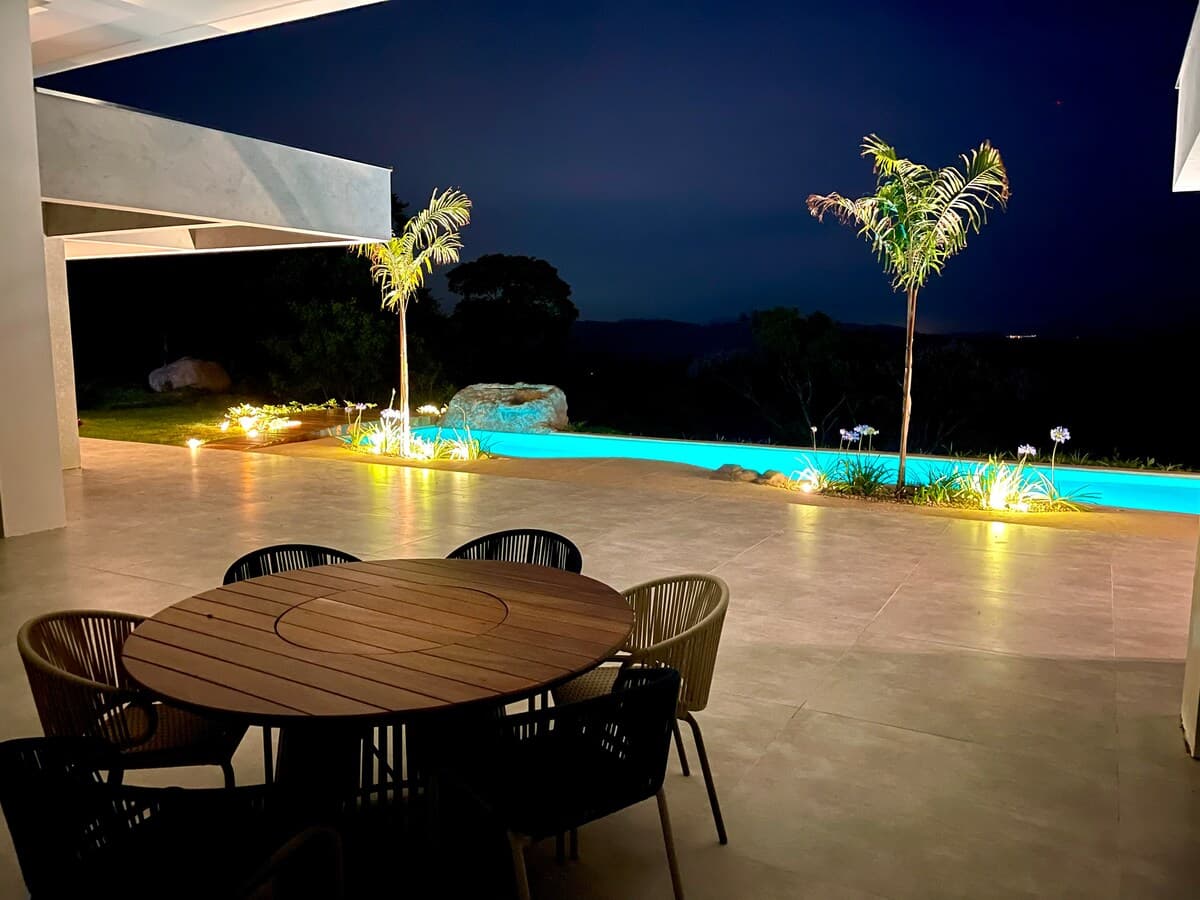 Mesa externa ao lado da piscina iluminada à noite