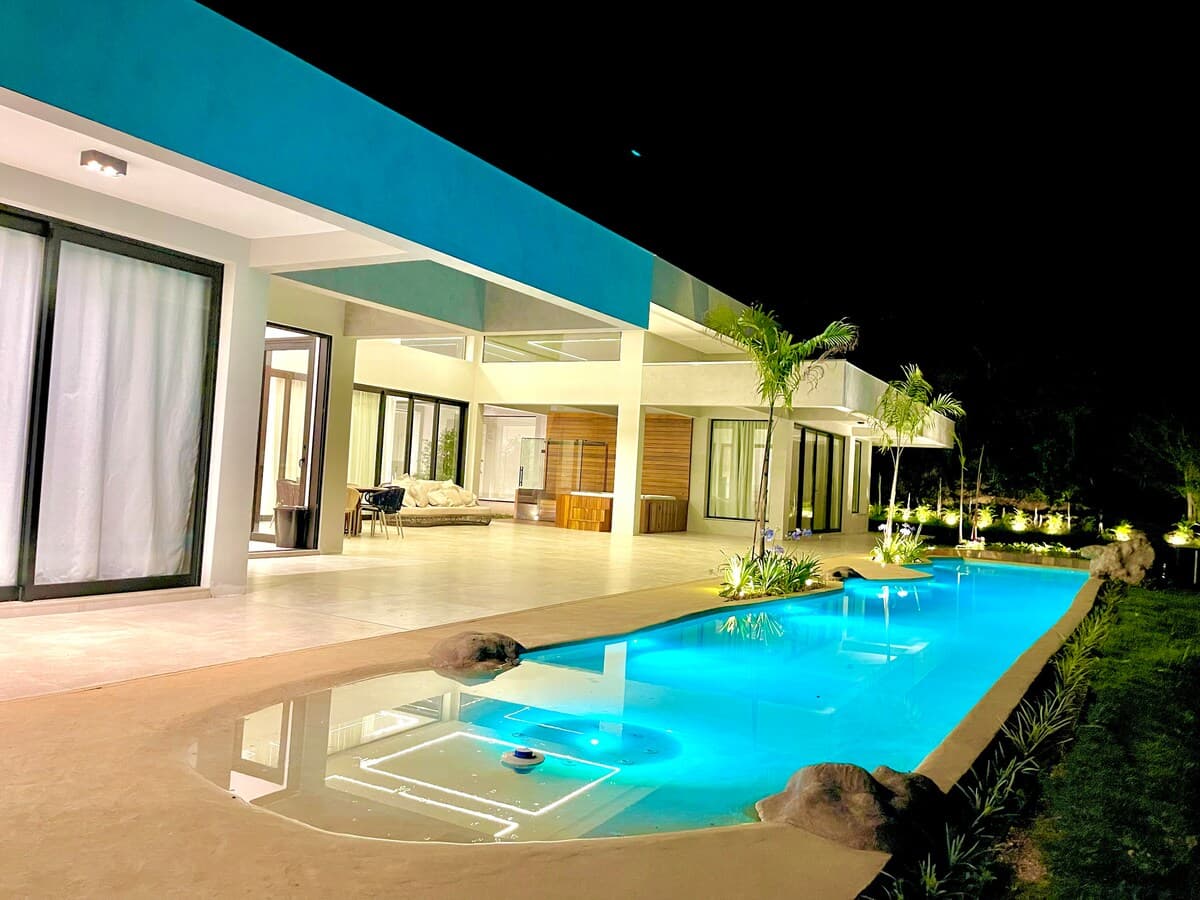 Piscina iluminada à noite com arquitetura contemporânea da casa